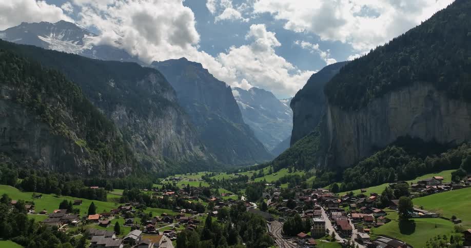 A village sprawls along a valley floor underneath the forest covered cliffs