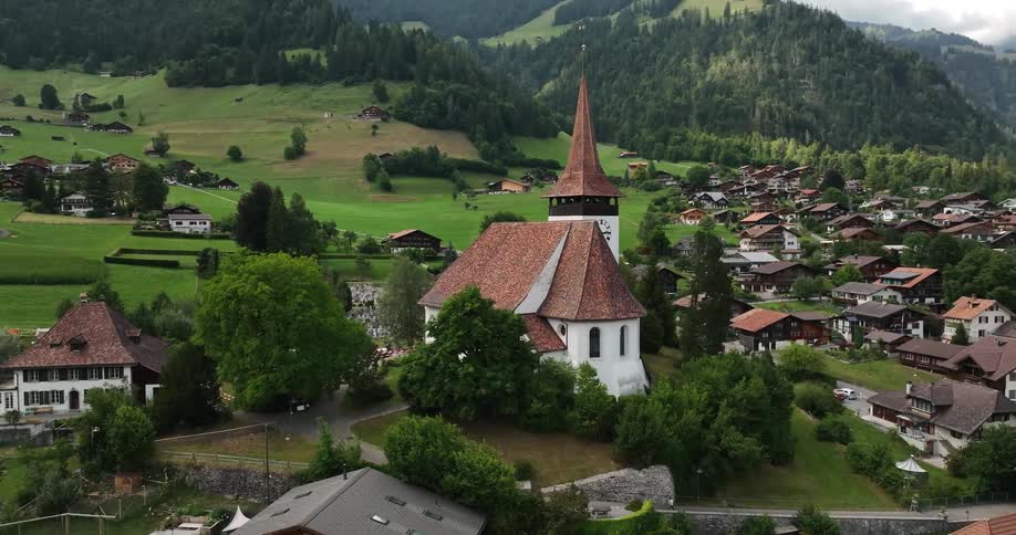 A church with its prominent steeple stands out amidst a picturesque mountain village