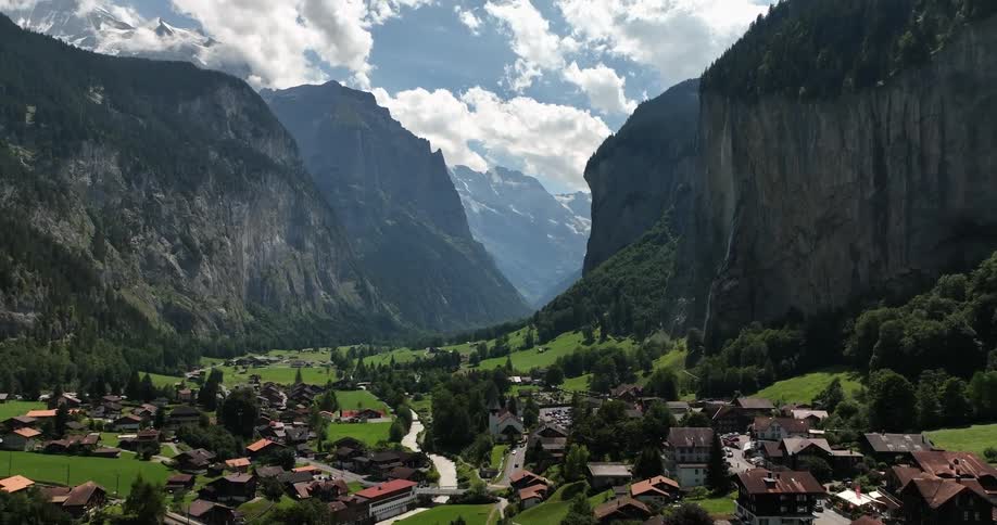 Aerial view of town in green valley between high and steep mountains