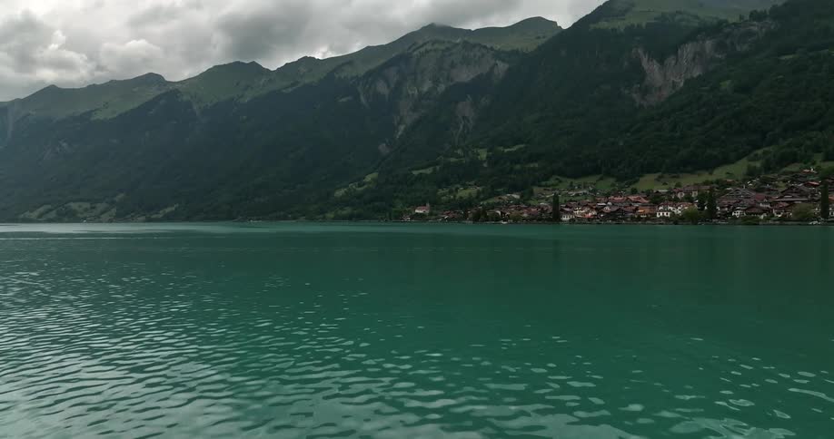 Aerial view of body of water and coastal town in front of high mountains