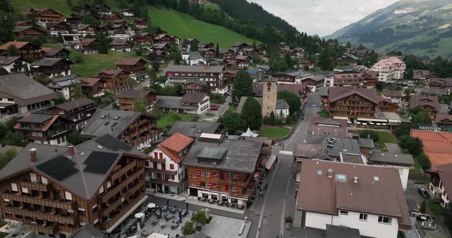 Aerial view of small city with buildings in green valley and high mountains