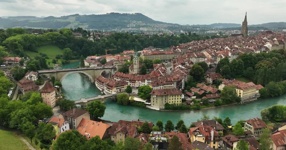A tall bridge spans a river that winds through a village