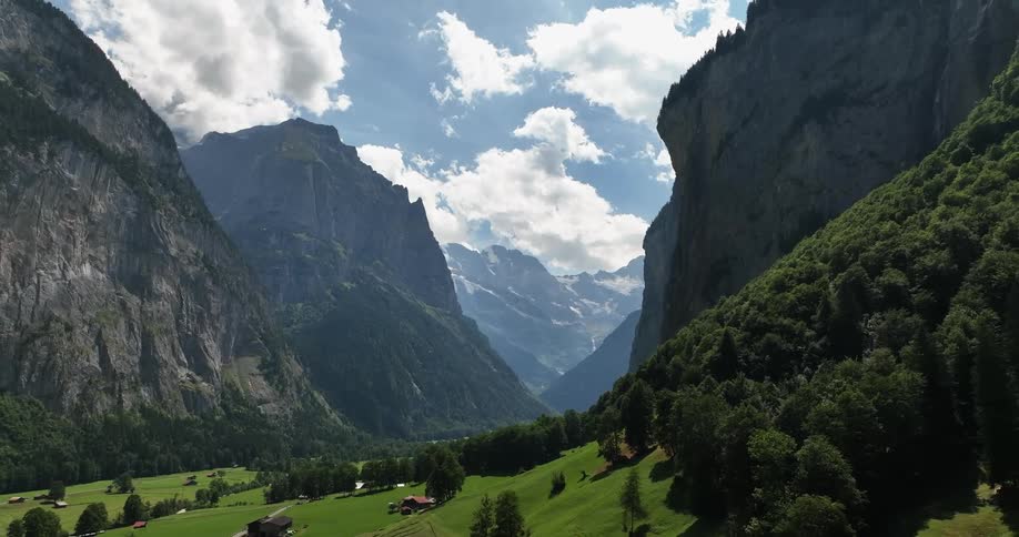 Aerial view of houses on the gentle slopes of a valley between tall mountains