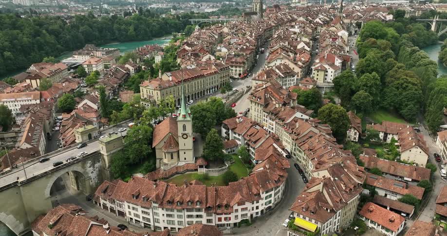 Vehicles drive down a bridge through a dense historical town