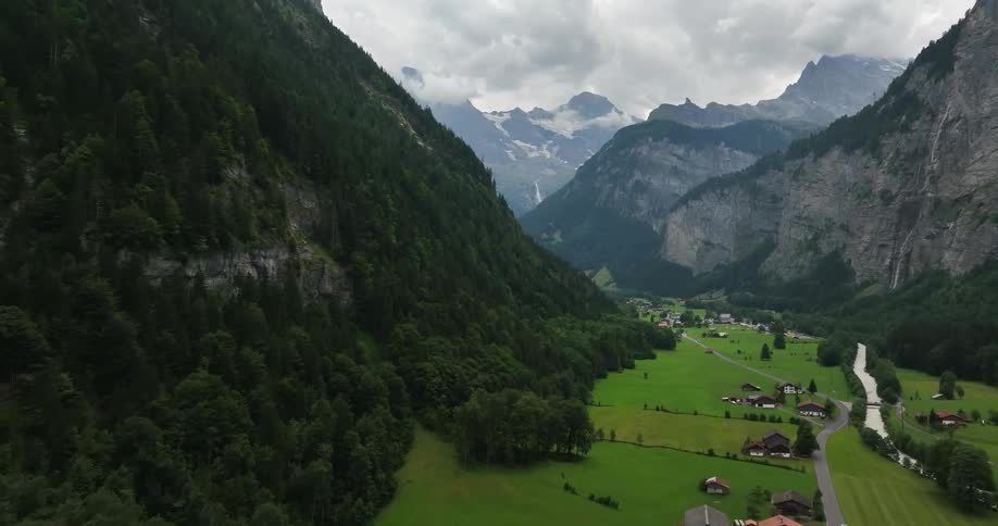 Aerial view of town in green valley and high steep mountains