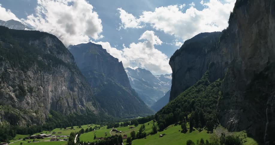 Aerial view of green valley and buildings between high and steep mountains