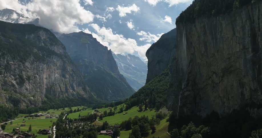 A mountain valley with trees on slopes and houses in the canyon during the day