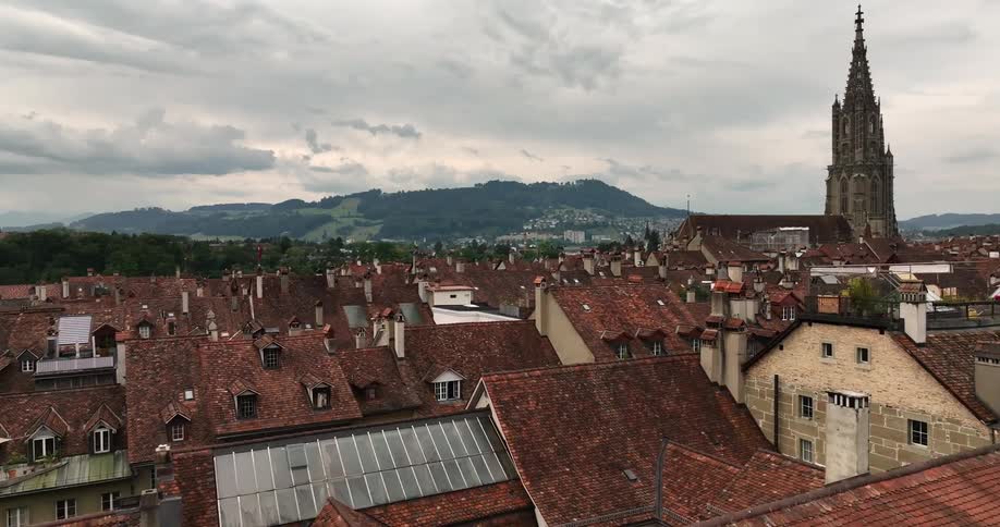 Aerial view of the tiled red roofs and towers on an european town near the mountains