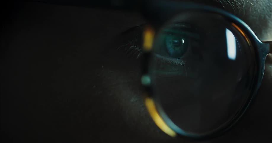 Closeup of mans blue eye with glasses looking at screen