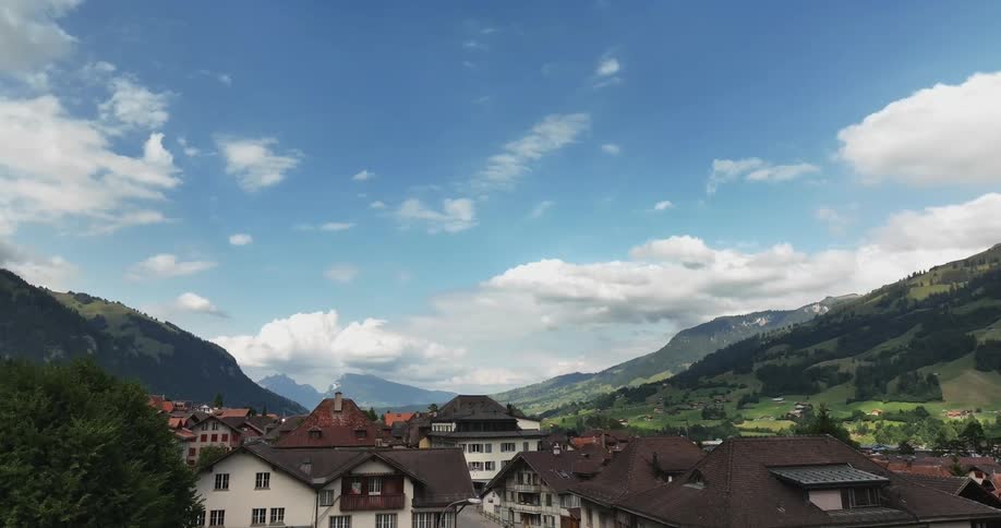 Aerial view of city streets in green valley and high steep mountains