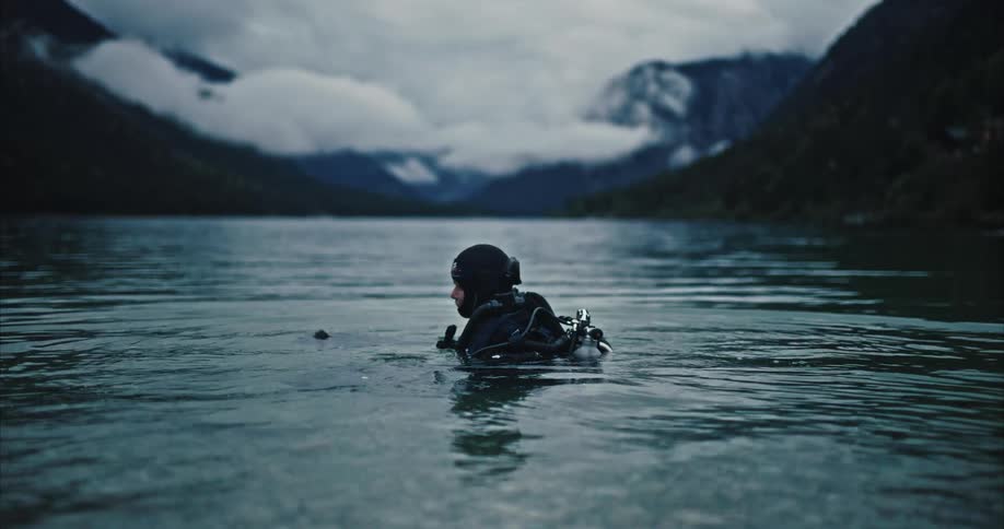 A diver is in the shallow part of a mountain lake