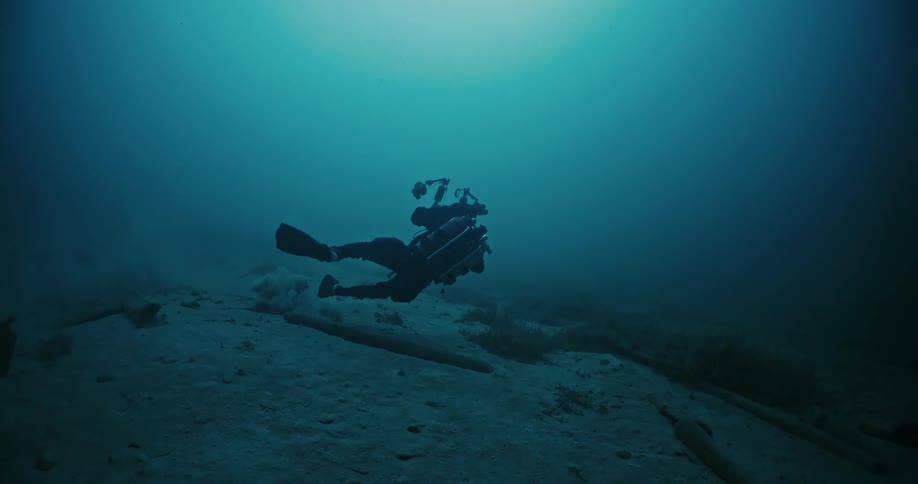 A scuba diver films underwater using an underwater camera