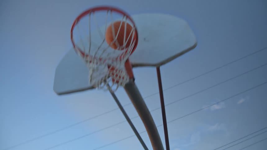 A man dribbles a basketball up to a basketball hoop and shoots it in with a layup
