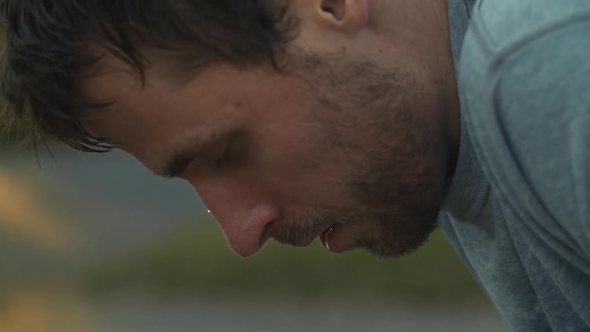 A man sweats as he leans over breathing hard