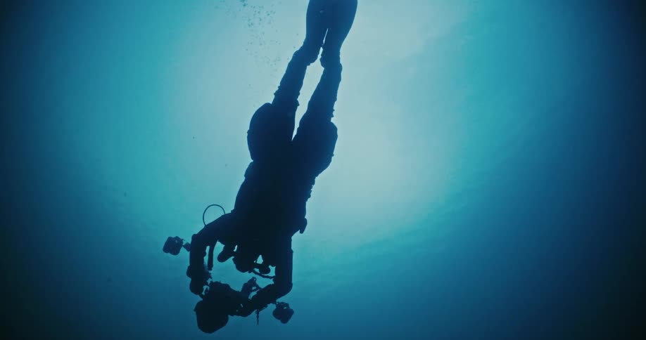 A person is scuba diving with cameras