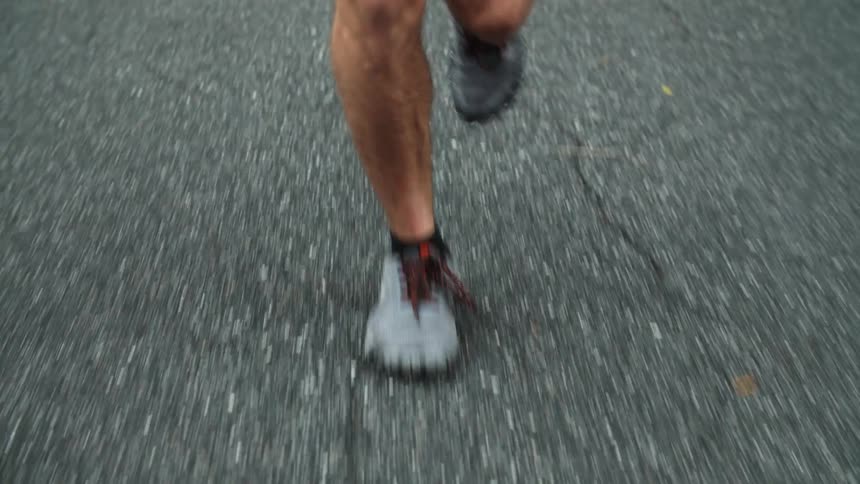 Man wearing gray sneakers jogs on road
