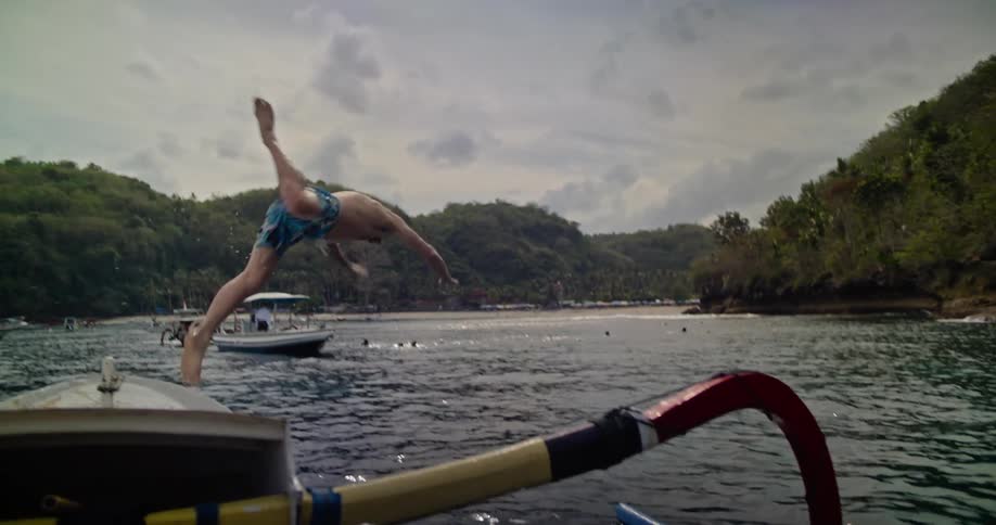 A man dives in the water from the boat