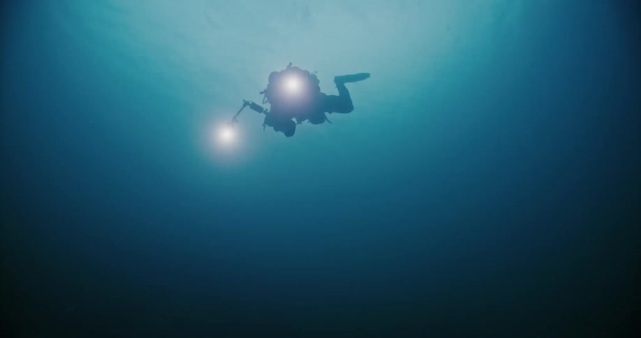 A diver gives an okay sign while filming underwater