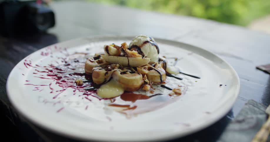 A person places a plate of dessert on a wooden table