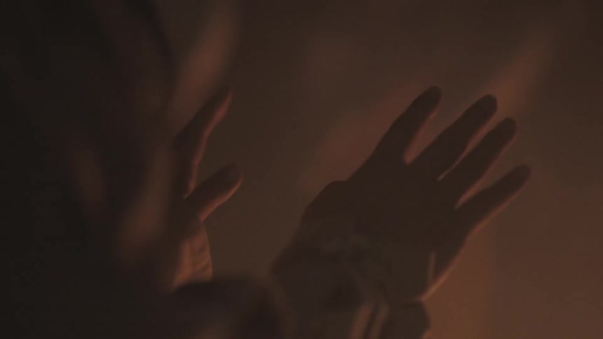 A person warms their hands beside a campfire
