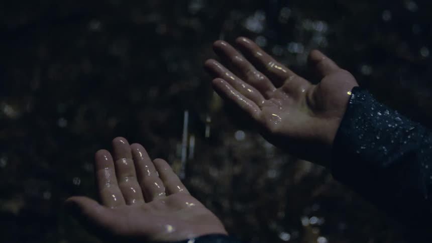 Close up of the hands of a man getting wet under the rain