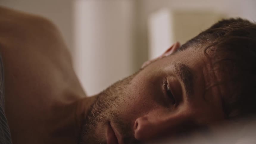 Close up of the face of a man waking up and rubbing his face with his hands