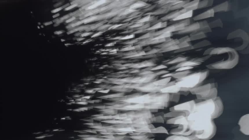 Bright white shapes flow and move through darkness