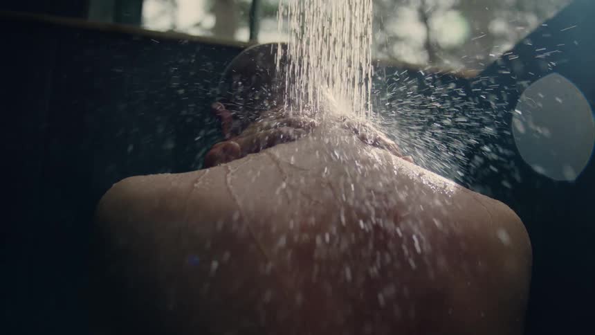 Back of the head of a man taking a shower on an outdoors bath