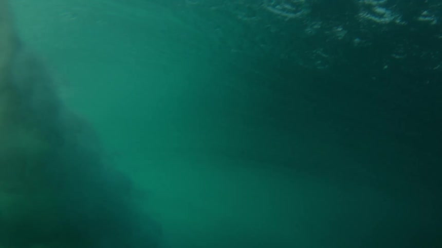 A huge wave rolls in splashing overhead and then looking up from underwater