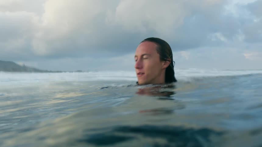 A diver holds a camera while coming up for air