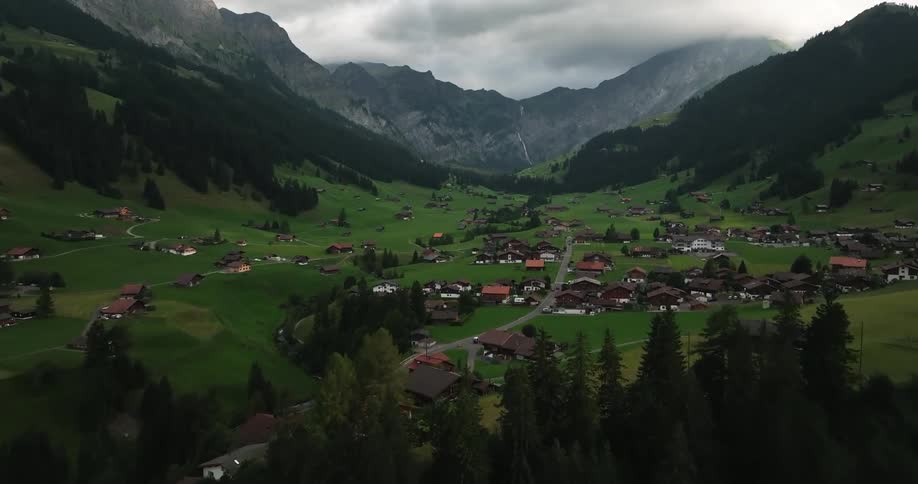 Aerial view of town in green valley and high steep mountains