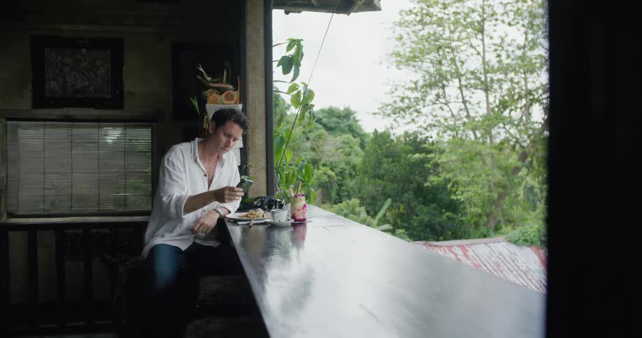 A man uses his phone while eating at a restaurant