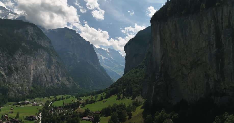 Aerial view of town in green valley and high and steep mountains