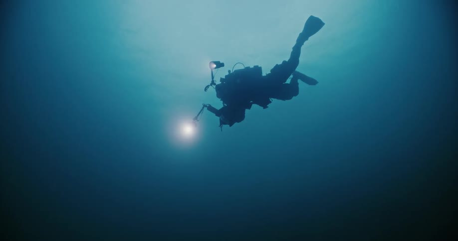 A scuba diver films underwater using an underwater camera