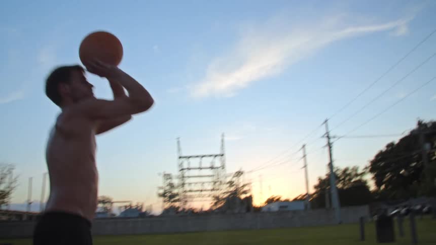Man playing basketball alone on court in park makes a shot