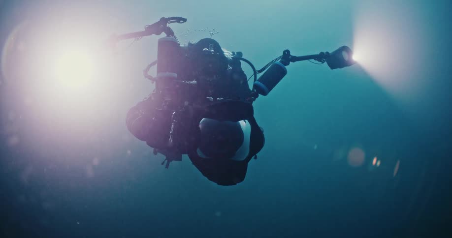 A person holds camera equipment as they perform a dive