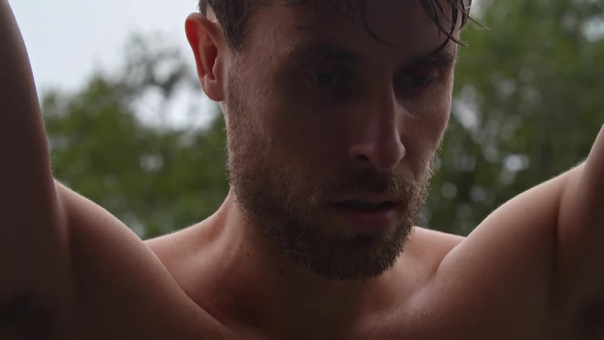 Sweaty man standing outdoors leans while breathing heavily