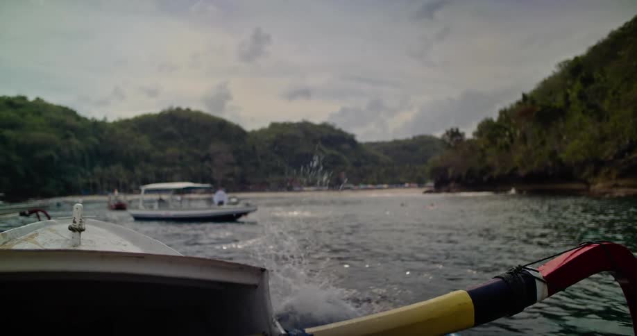 Shirtless man jumps from a boat into a river near a beach on the tropics