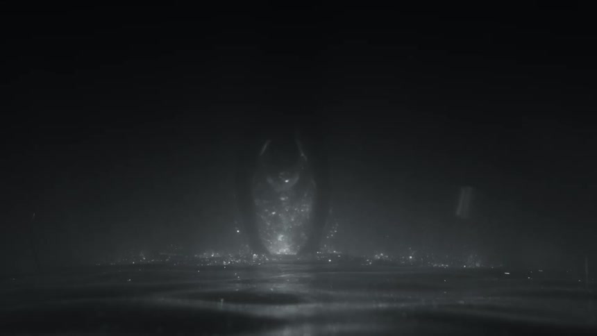 An upside down slow motion shot of a man jumping into a dark body of water and sinking to the bottom