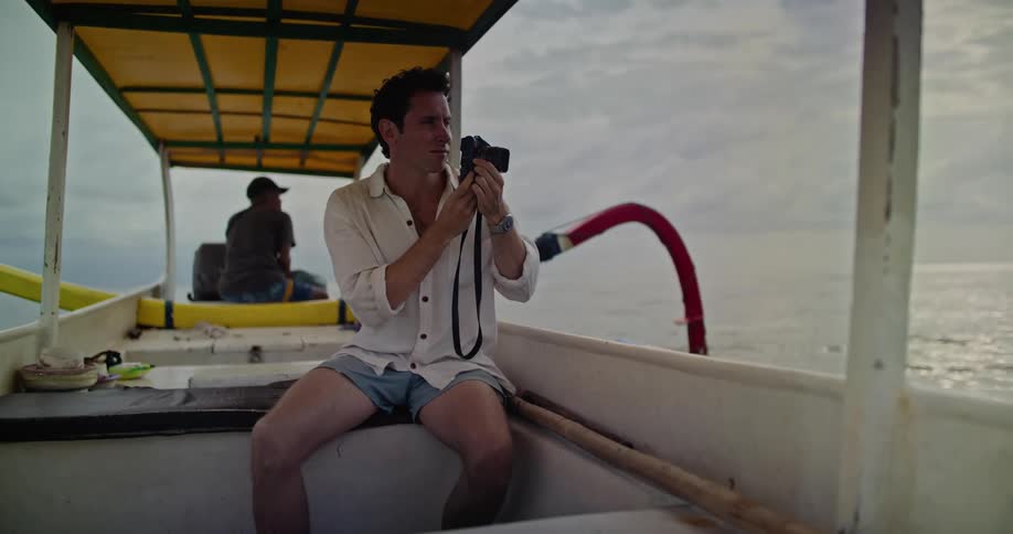 A man takes photos with his camera while sitting in the back of a pontoon boat