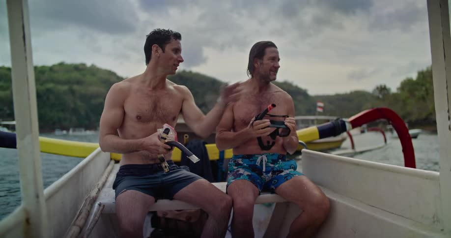 Two men are sitting on a boat holding a snorkel and talking
