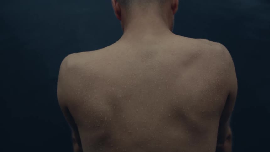 Close up of the back of a shritless person against a dark background