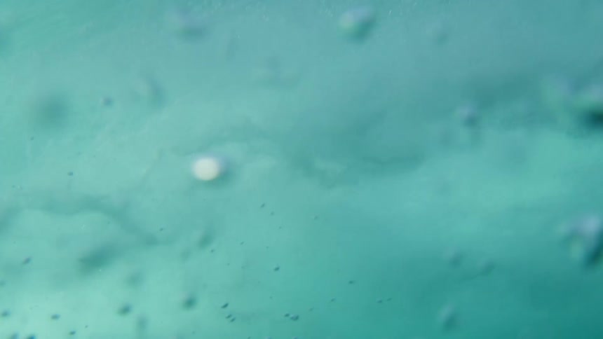 Underwater footage of air bubbles forming under an ocean wave rolling overhead