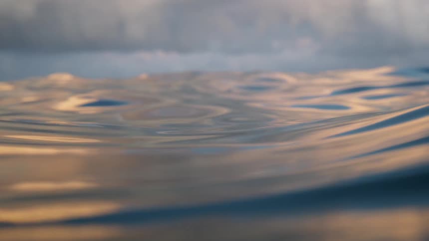 Small gentle waves on the surface of the ocean with a distant ship on the horizon