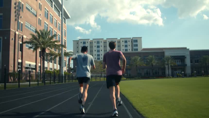 Two men running against each other on a track in the city at daytime