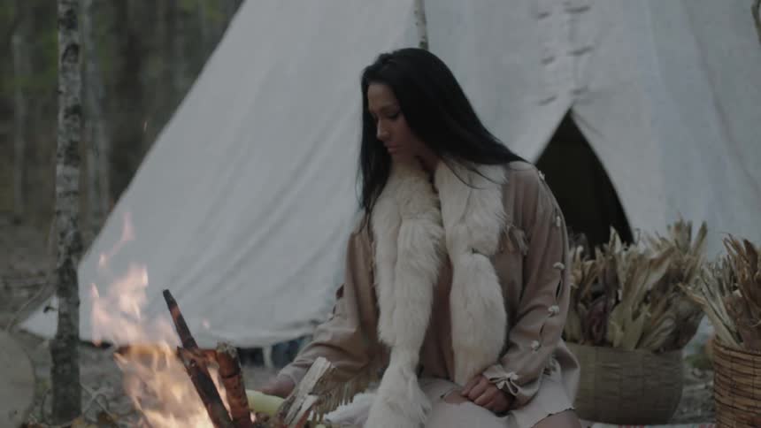 Tribal woman preparing food in front of a small fire
