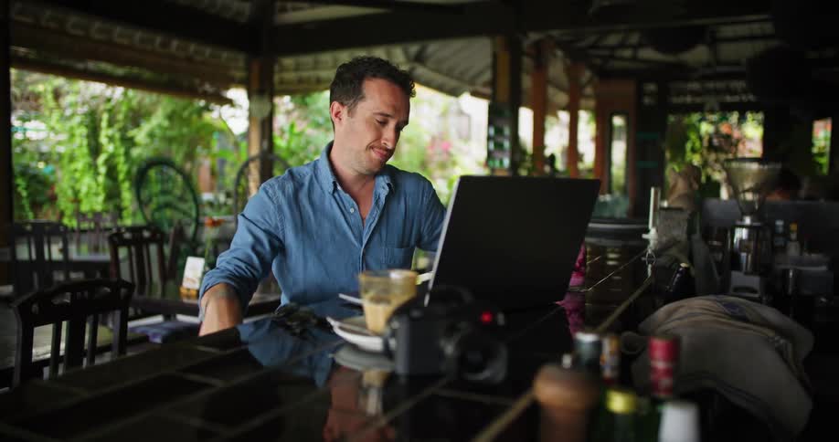 A man works on his laptop while sitting at the bar in a restaurant