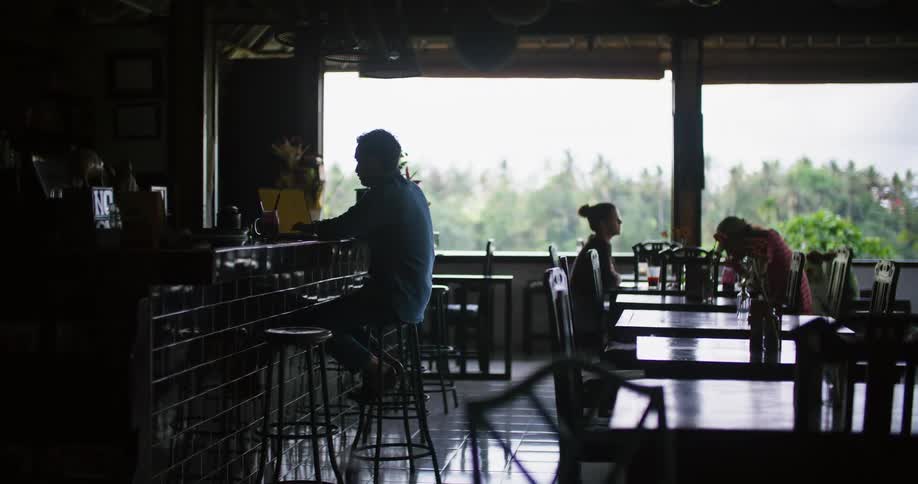 Two people eat in a restaurant while another customer works on his laptop at the bar