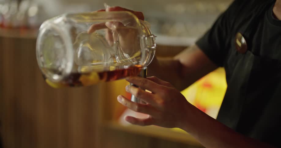 Bartender mixes drink while coworker dries and puts up equipment in the background