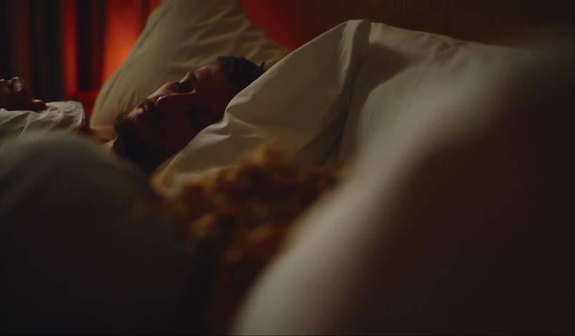 Couple lies on bed in dim bedroom together sleeping